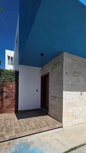 A modern building with a blue exterior, a stone wall with the number 19, and a wooden fence. - Sunflower Villa Punta Cana (Punta Cana)