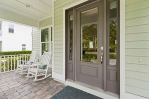 A front porch with a dark brown door, white rocking chairs, and a white exterior wall. - Sunrise on First - Close walk to beach (Fernandina Beach)