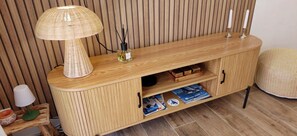Een houten console tafel met een geweven lamp, kaarshouders en tijdschriften.