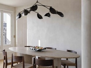 A round dining table with a bowl of fruit, surrounded by six chairs with woven seats. - Spacious apartment overlooking the Eiffel Tower (Paris)