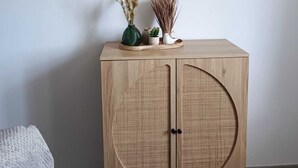 Ein Zimmer mit einem Holzschrank, gerahmten Bildern an der Wand und einem kleinen Tisch mit Dekoration.