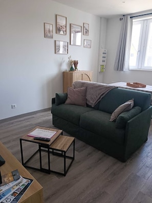 Un saló amb un sofà verd, una taula de centre de fusta i un moble de fusta amb objectes decoratius.