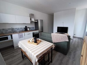 Un espace de vie compact comprenant un coin cuisine, une table à manger, un canapé et un téléviseur.