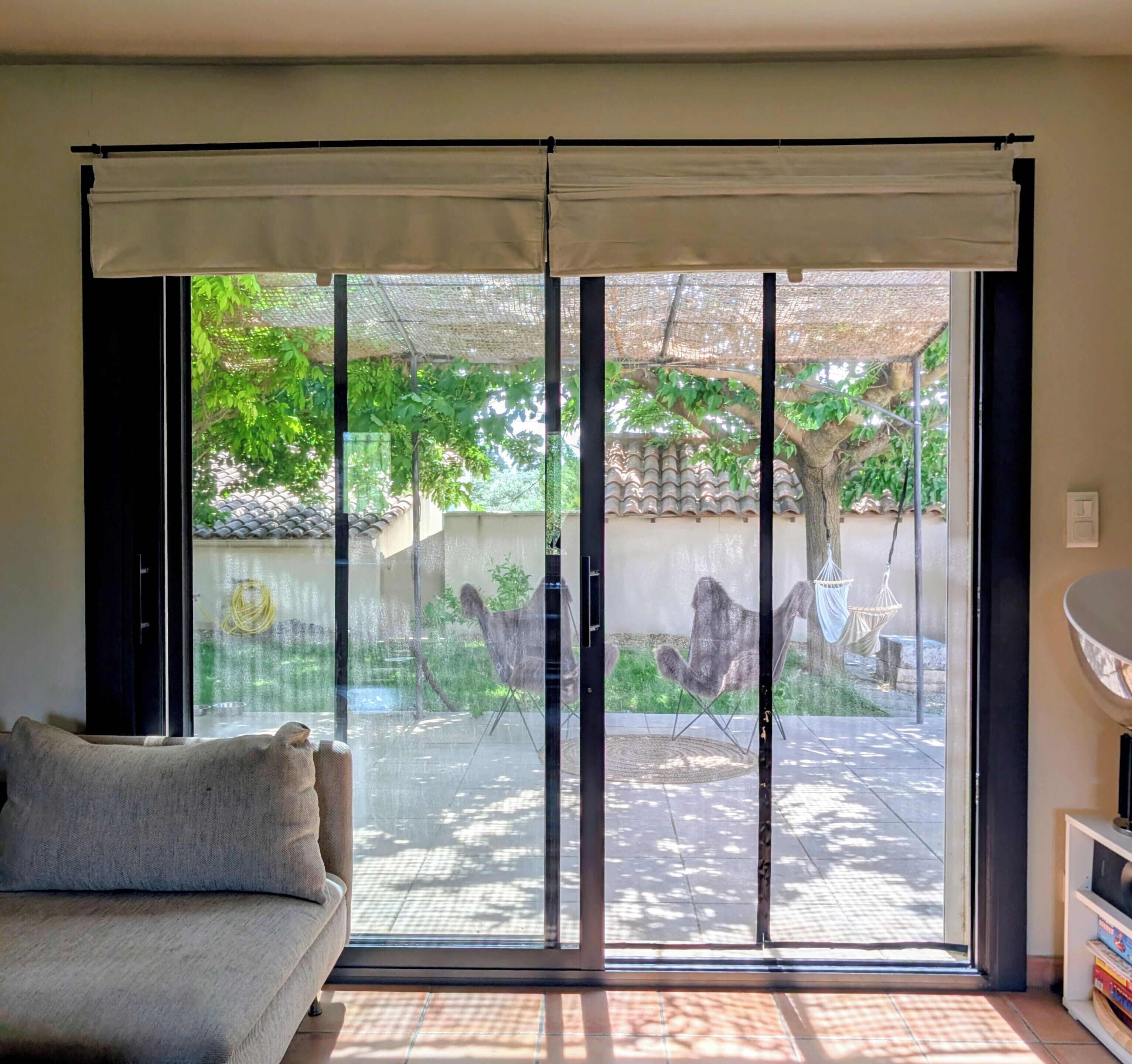 Una habitación con puerta corrediza de vidrio que da a un espacio exterior con una hamaca y un árbol.