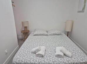 Un petit lit, bien fait, avec une literie à motifs floraux, deux oreillers et deux serviettes enroulées posées sur le lit.