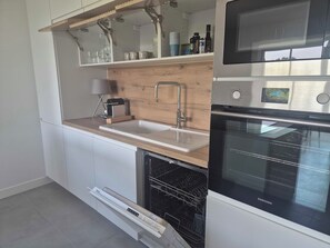 Eine moderne Küche mit einem eingebauten Geschirrspüler, einem Backofen und einer Holzausziehtheke.