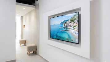 Een modern interieur met een grote flatscreen televisie aan een witte muur, een minimalistisch design en een opgeruimde, rustige ruimte.