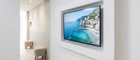 A modern interior with a large flat-screen TV mounted on a white wall, a minimalist design, and a clean, uncluttered space.