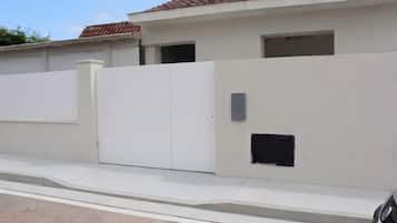 Un edificio bianco con tetto a tegole, ingresso con cancello e una piccola finestra.
