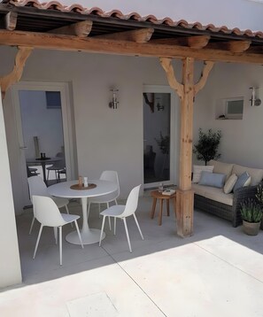 Un patio couvert comprenant une table ronde et des chaises, un canapé et une plante en pot.