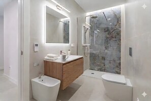 Une salle de bain moderne avec un meuble-lavabo en bois, un grand miroir, une douche avec une paroi en verre et des toilettes.