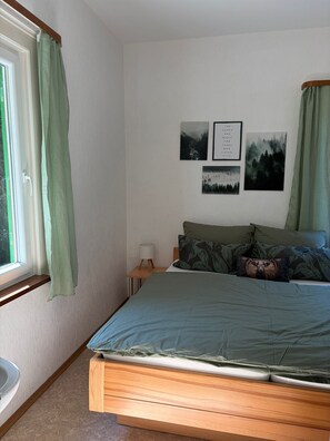 A bedroom with a bed, a nightstand, a lamp, and three framed pictures on the wall.