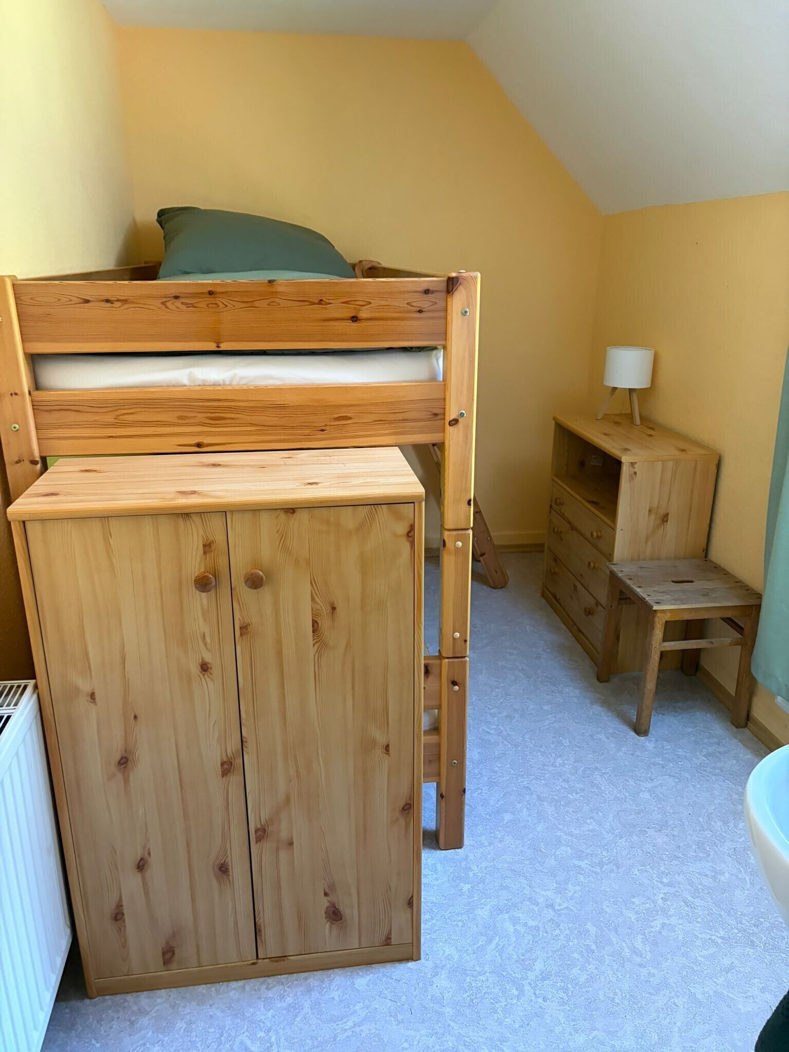 Ein Zimmer mit einem Etagenbett, einem kleinen Holztisch, einem Stuhl und einer Lampe.