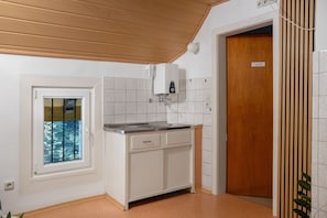 A kitchen with a window, a built-in oven, and a wooden door. - Holiday Home 'Hirschglück' with Private Terrace and Garden in Alpirsbach, Black Forest (Alpirsbach)