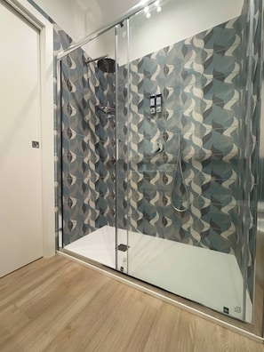 A glass-enclosed shower with a patterned wall, a metal handle, and a control panel. - Room-elegant Suite Between Sorrento and (Castellammare di Stabia)