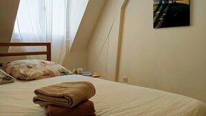 A bedroom with a bed, pillows, a painting, and a window with curtains. - Le Comptoir des Halles - Tours center (Tours)
