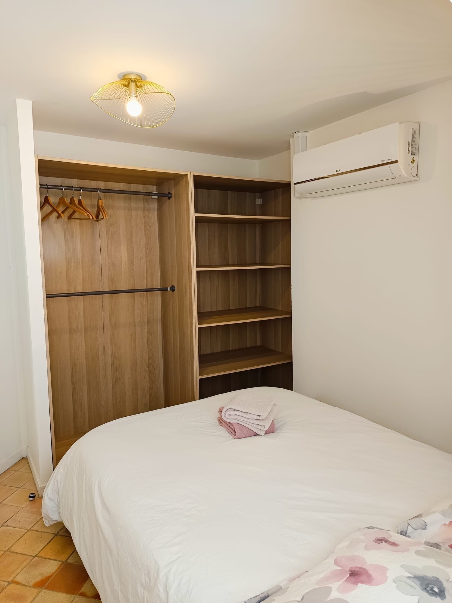 Une chambre à coucher avec un lit, une armoire en bois et un luminaire fixé au plafond.