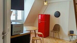 A compact kitchen with a microwave, a red refrigerator, a dining table with two chairs, and a ceiling fan. - Le Comptoir des Halles - Tours center (Tours)