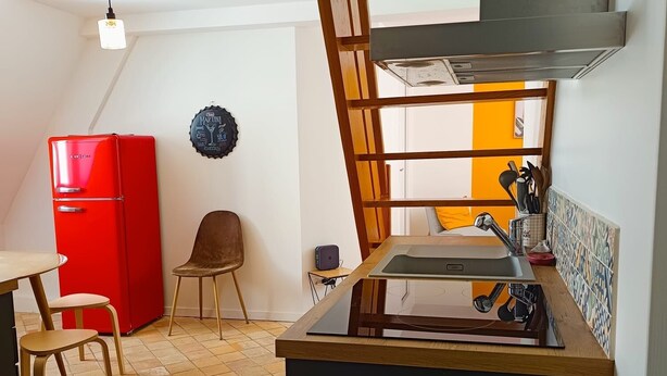 A compact kitchen with a red refrigerator, a wooden chair, a small table, and a tiled floor. - Le Comptoir des Halles - Tours center (Tours)
