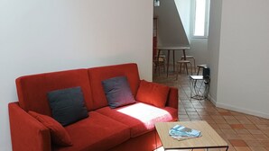 A red sofa with two pillows, a small wooden coffee table, and a geometric pendant light. - Le Comptoir des Halles - Tours center (Tours)