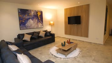 A living room with a sofa, a coffee table, a TV mounted on the wall, and a painting on the wall.