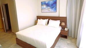 A hotel room with a bed, a nightstand, a phone, and a painting on the wall.