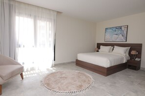 A bedroom with a bed, a nightstand, a chair, and a round rug. - Settle inn Jebal Apartments (Cairo)