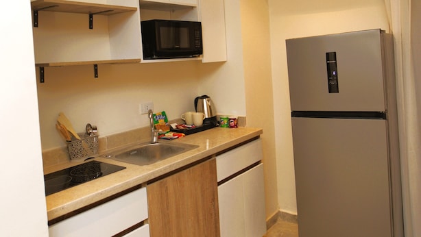 A compact kitchen with a microwave, refrigerator, and built-in oven.
