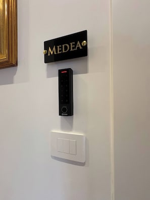 A wall-mounted electronic keypad, a nameplate, and a light switch.