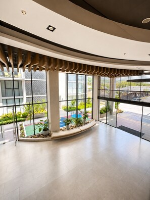 A spacious lobby with large windows, a curved ceiling, and a small outdoor seating area with plants. - Apartamento moderno en pozos colorados (Santa Marta)