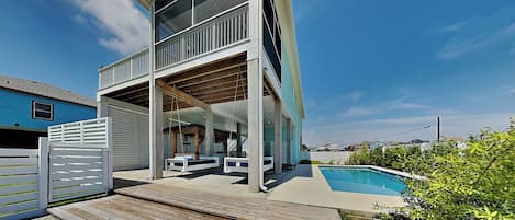 Ein modernes, zweistöckiges Haus mit Balkon, Pool und Holzterrasse.