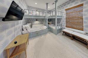 A bedroom with bunk beds, a desk, and a window with blinds. - Tiki Pool Club (Galveston)