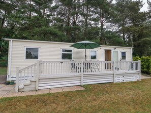 A mobile home with a front porch, a staircase, and a green umbrella. - Foxglove 4 (Ringwood)