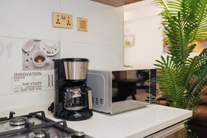 A kitchen with a coffee maker, microwave, and a wall with a coffee cup and spoon. - Luxurious Breakaway in Nairobi, Kilimani surrounded by all amenities. (Nairobi)