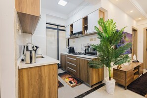 A modern kitchen with wooden cabinets, a coffee machine, and a potted plant. - Luxurious Breakaway in Nairobi, Kilimani surrounded by all amenities. (Nairobi)