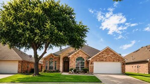 A residential house with a brick facade, a large front lawn, and a garage. - Executive 4BR Retreat Mins to AT&T Stadium (Arlington)