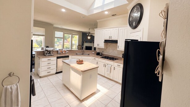 A modern kitchen with white cabinets, a black refrigerator, and a skylight. - Executive 4BR Retreat Mins to AT&T Stadium (Arlington)