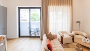 Un salon moderne comprenant un canapé, deux fauteuils, une table basse, un lampadaire et une porte-fenêtre coulissante donnant sur un espace extérieur avec une table et des chaises.