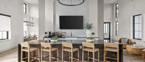Una cocina moderna con una isla grande, iluminación colgante y una pantalla de televisión grande.