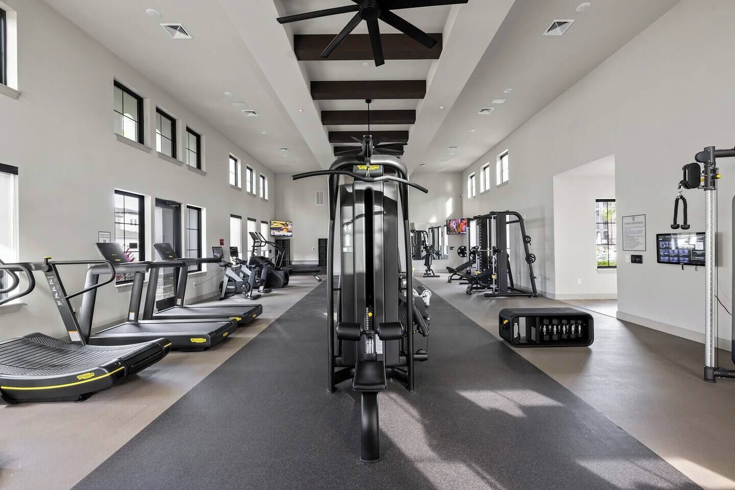 Une salle de sport moderne équipée de tapis de course, de vélos elliptiques et de matériel de musculation.