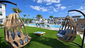 Ein Poolbereich mit Hängestühlen, einem Pool und einer Rasenfläche.