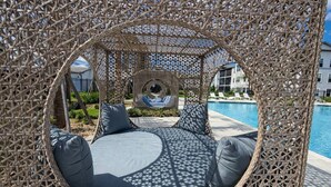 Ein runder Sitzbereich im Freien mit Blick auf einen Pool und ein Gebäude im Hintergrund.
