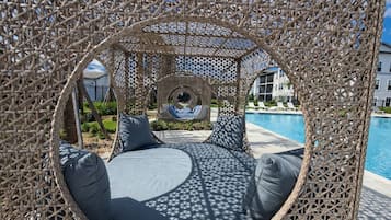 Ein runder Sitzbereich im Freien mit Blick auf einen Pool und ein Gebäude im Hintergrund.