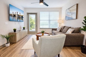 A living room with a sofa, coffee table, and a TV mounted on the wall.