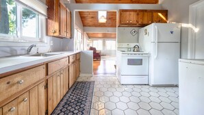 A kitchen with wooden cabinets, a white refrigerator, and a hexagonal tile floor.