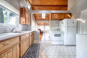 A kitchen with wooden cabinets, a white refrigerator, and a hexagonal tile floor.