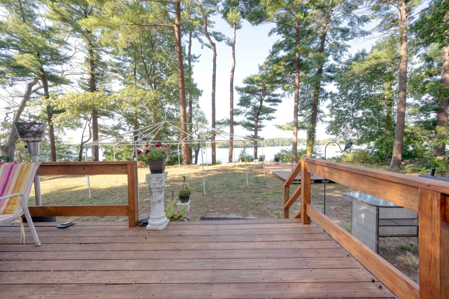 A wooden deck with a railing, a hanging flower pot, and a bench.