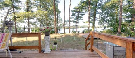 A wooden deck with a railing, a hanging flower pot, and a bench.