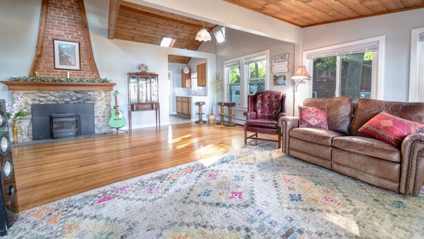 A spacious living room with a fireplace, leather sofa, and a colorful rug.