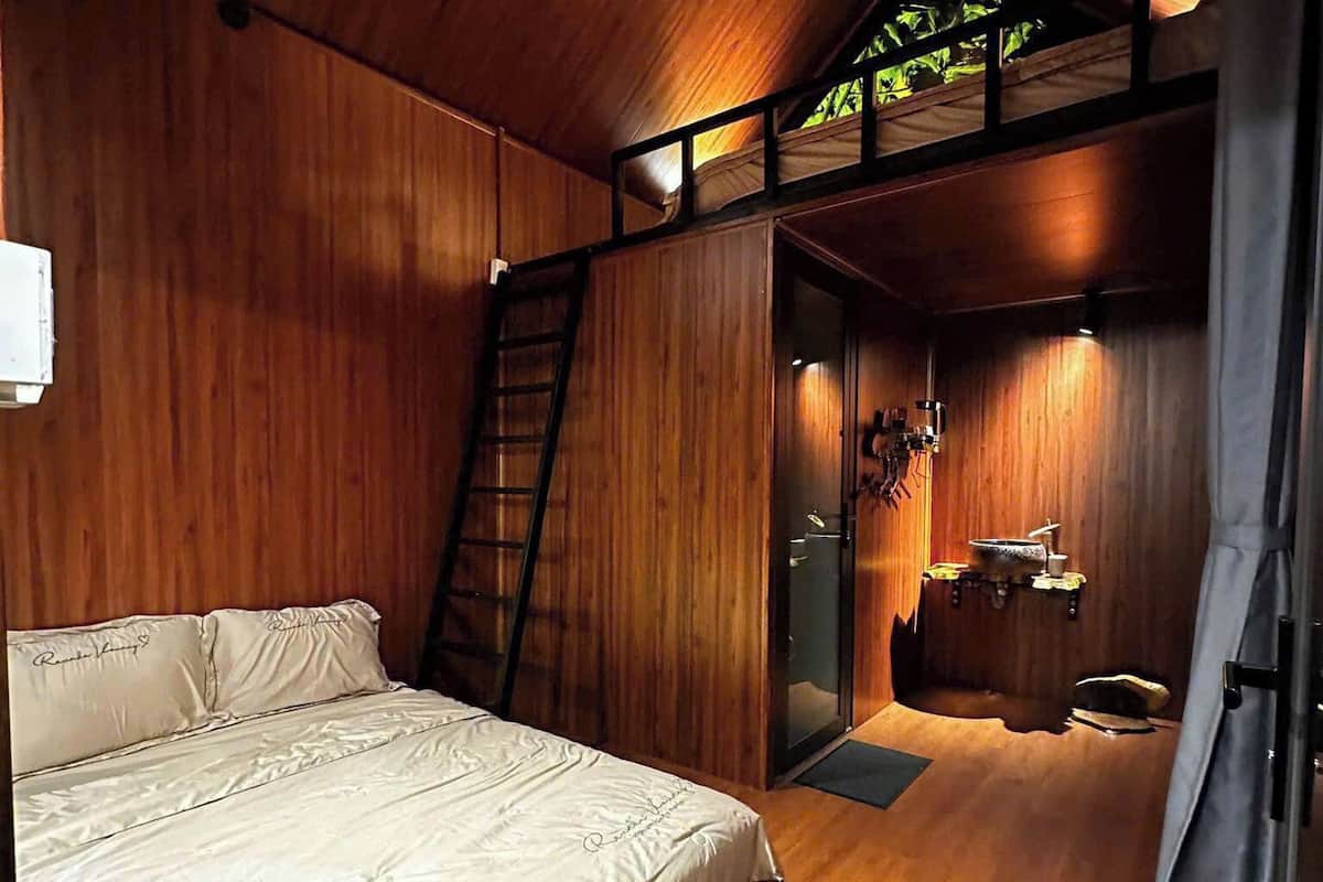 Una habitación de madera con una cama, una escalera y una pequeña kitchenette.
